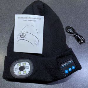Black LED music hat with user manual and cable on a gray surface