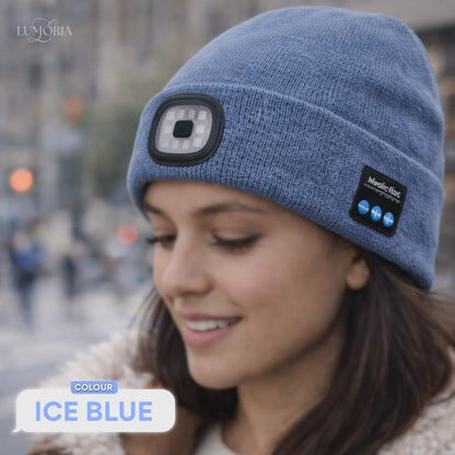 Woman wearing the GlowSound Beanie™ in ice blue with Bluetooth audio controls and a front LED light during everyday wear