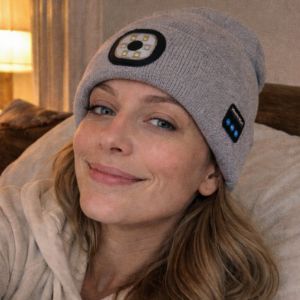 Person wearing a gray beanie with a unique design, sitting on a couch.